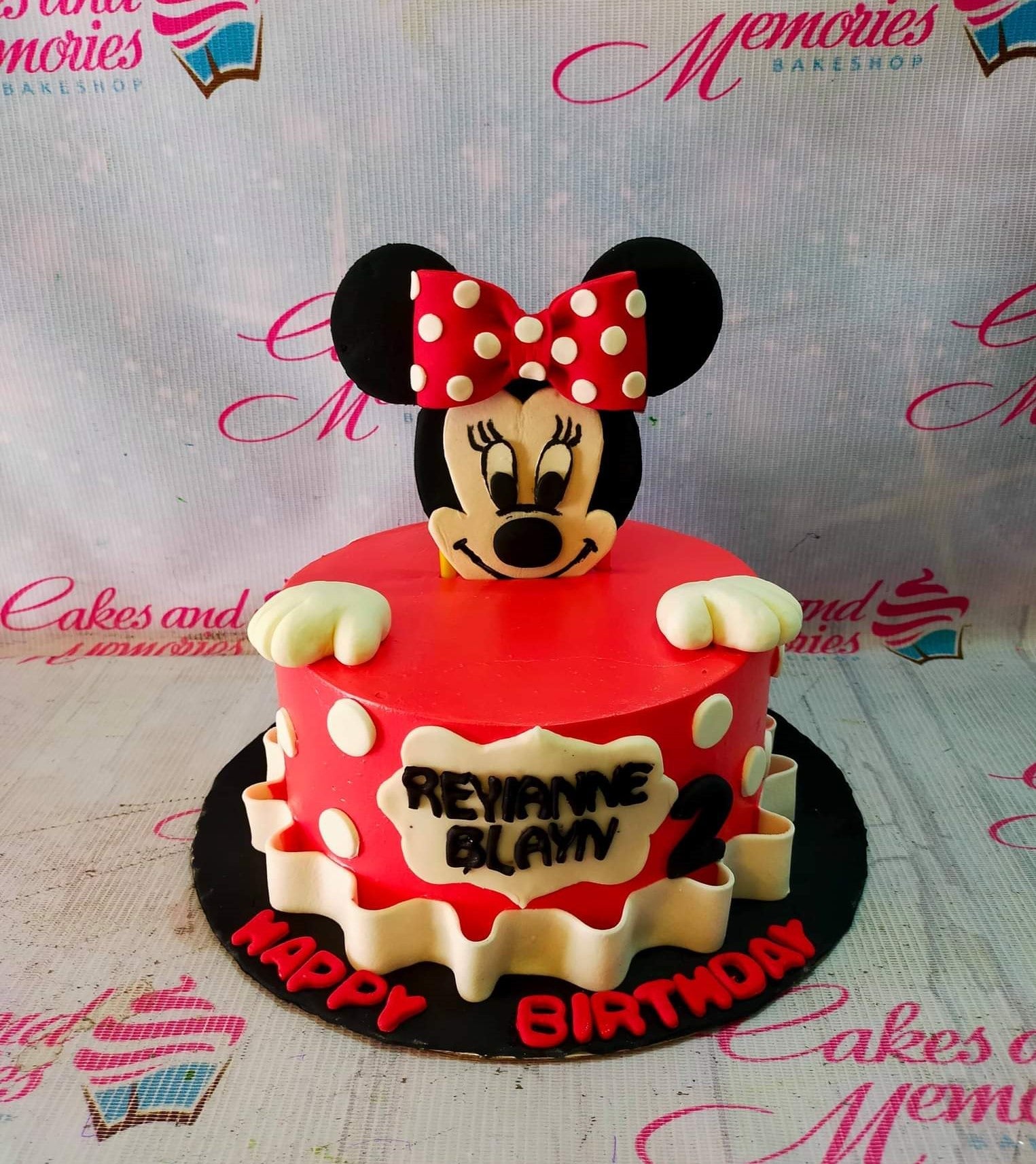 Red Minnie Mouse themed fondant cake with white polka dots, a large Minnie topper, and a white ruffled base. Red Minnie Mouse themed fondant cake with white polka dots, a large Minnie topper, and a white ruffled base.