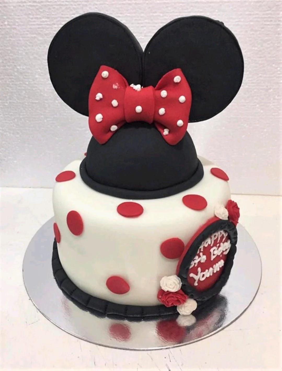 White and red 1 Tier Fondant Minnie Mouse cake, with a large black Minnie Mouse head topper and red polka dots.