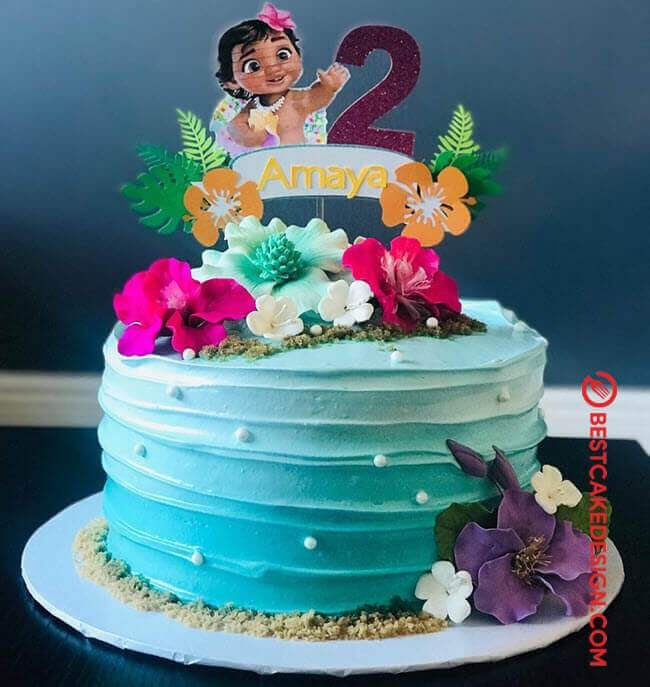 Moana themed birthday cake with blue ombre ruffled icing, edible flowers, and a Moana character printout topper. Moana themed birthday cake with blue ombre ruffled icing, edible flowers, and a Moana character printout topper.