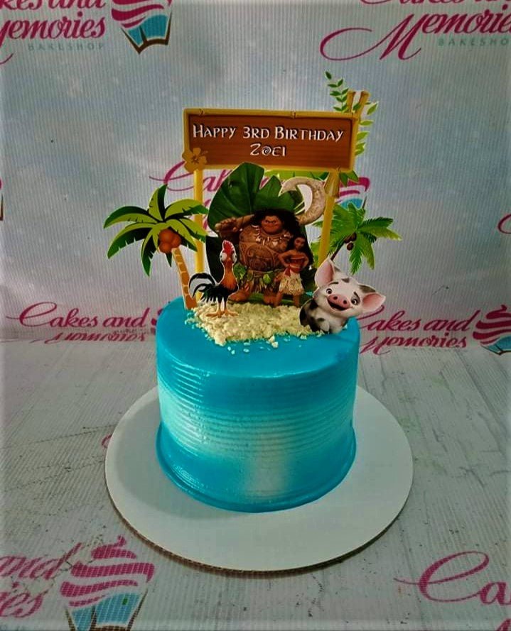 Moana themed birthday cake with blue gradient icing, sand texture, and character printouts of Moana, Maui, Hei Hei, and Pua. Moana themed birthday cake with blue gradient icing, sand texture, and character printouts of Moana, Maui, Hei Hei, and Pua.