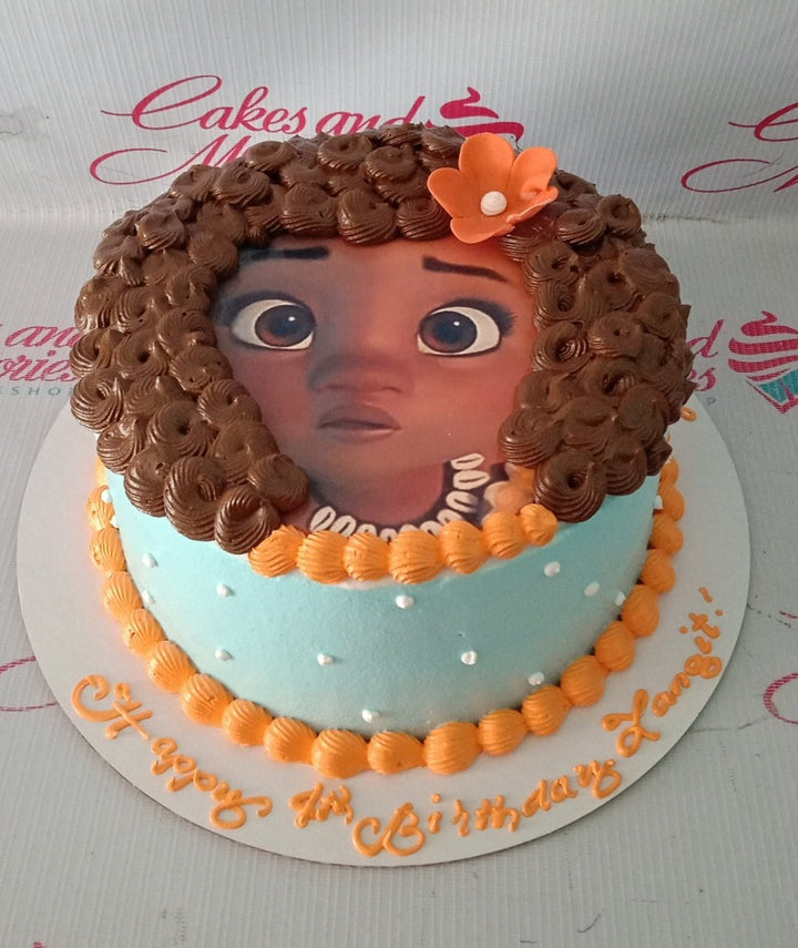 Moana themed birthday cake with light blue icing, orange borders, and a large Moana printout with brown icing hair. Moana themed birthday cake with light blue icing, orange borders, and a large Moana printout with brown icing hair.