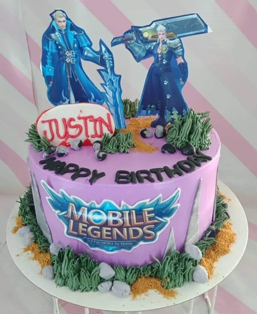 Mobile Legends themed purple birthday cake with character printouts, green icing grass, and edible rocks. Mobile Legends themed purple birthday cake with character printouts, green icing grass, and edible rocks.