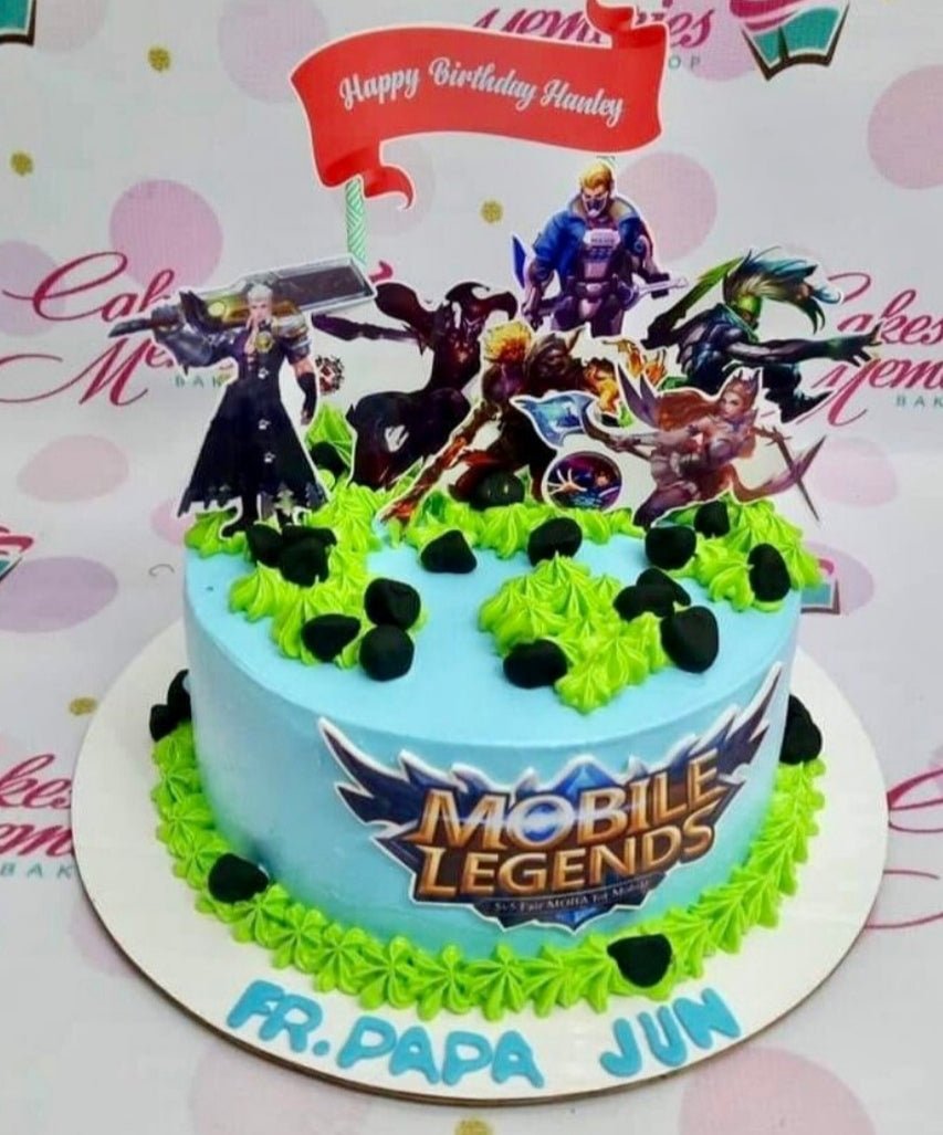 Light blue Mobile Legends themed birthday cake with green icing grass, black fondant rocks, and character printouts. Light blue Mobile Legends themed birthday cake with green icing grass, black fondant rocks, and character printouts.