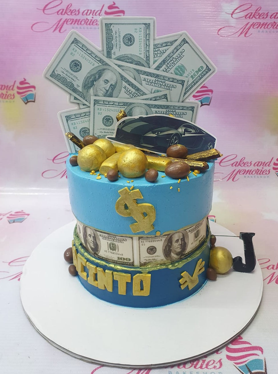 Blue money themed cake with dollar bill printouts, gold bars, and a black sports car topper. Blue money themed cake with dollar bill printouts, gold bars, and a black sports car topper.