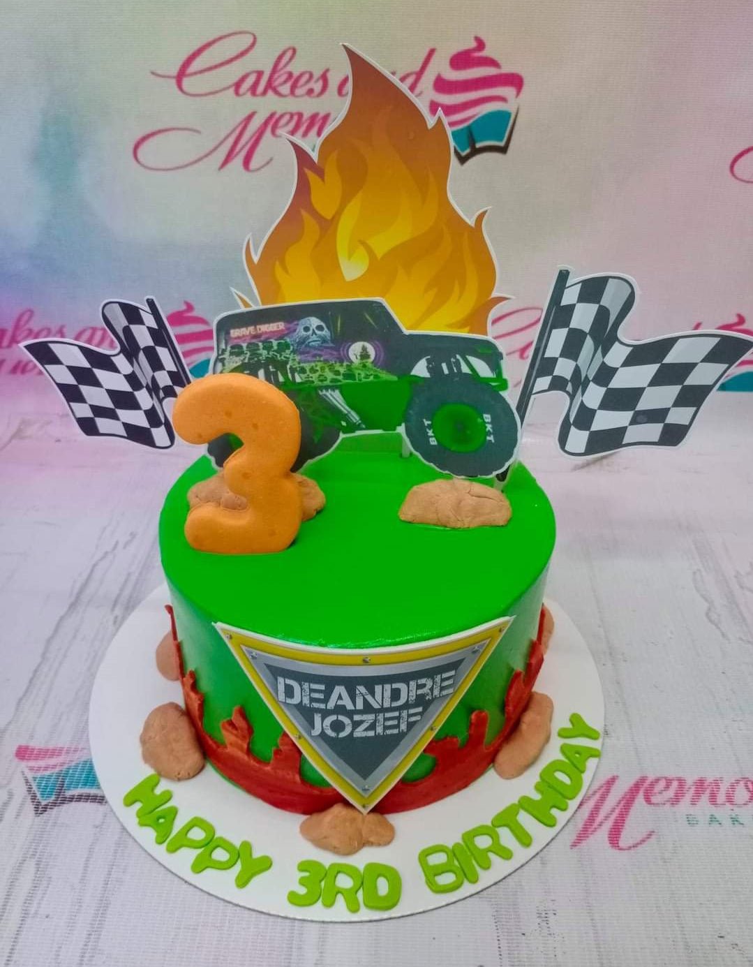 Green monster truck themed birthday cake with Grave Digger printout, fire topper, and checkered flags. Green monster truck themed birthday cake with Grave Digger printout, fire topper, and checkered flags.