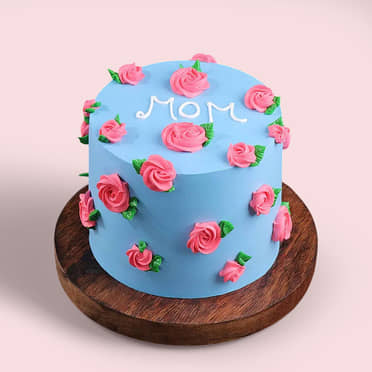 Light blue minimalist cake decorated with pink piped icing roses and green leaves with a white icing message saying MOM on top. Light blue minimalist cake decorated with pink piped icing roses and green leaves with a white icing message saying MOM on top.