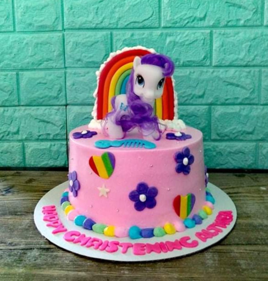 Pink My Little Pony christening cake with a 3D Rarity figure, rainbow backdrop, and purple fondant flowers. Pink My Little Pony christening cake with a 3D Rarity figure, rainbow backdrop, and purple fondant flowers.