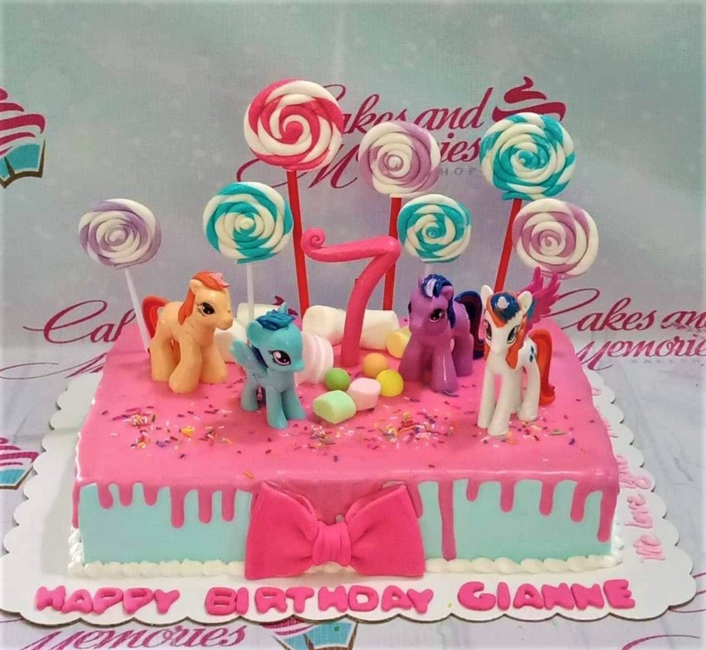 Rectangle My Little Pony birthday cake with pink drip icing, pony figurines, and colorful lollipop toppers. Rectangle My Little Pony birthday cake with pink drip icing, pony figurines, and colorful lollipop toppers.