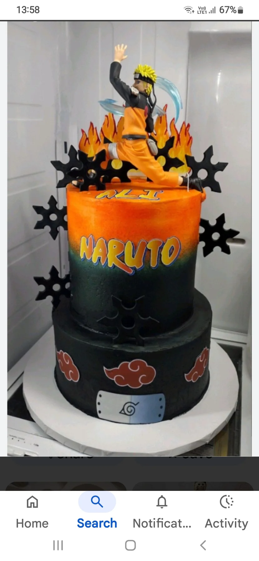 Two-tier Naruto themed cake with orange and black gradient icing, a Naruto figurine on top, and black shuriken accents. Two-tier Naruto themed cake with orange and black gradient icing, a Naruto figurine on top, and black shuriken accents.