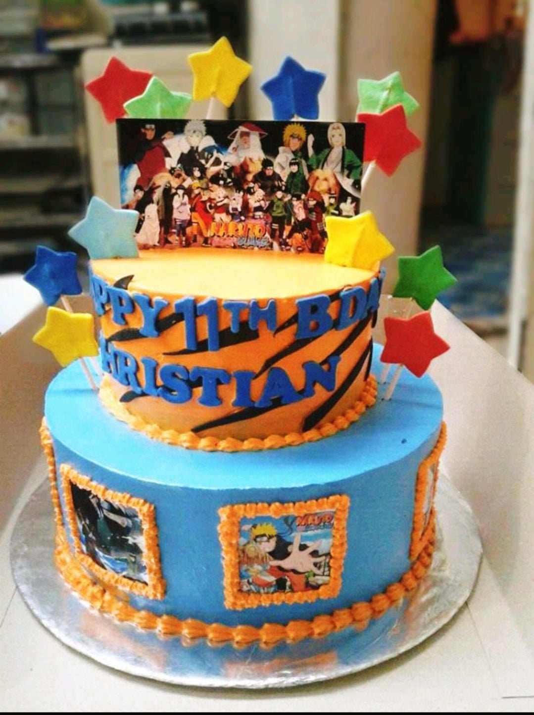 Two-tier Naruto themed birthday cake with orange and blue icing, character printouts, and colorful fondant stars. Two-tier Naruto themed birthday cake with orange and blue icing, character printouts, and colorful fondant stars.