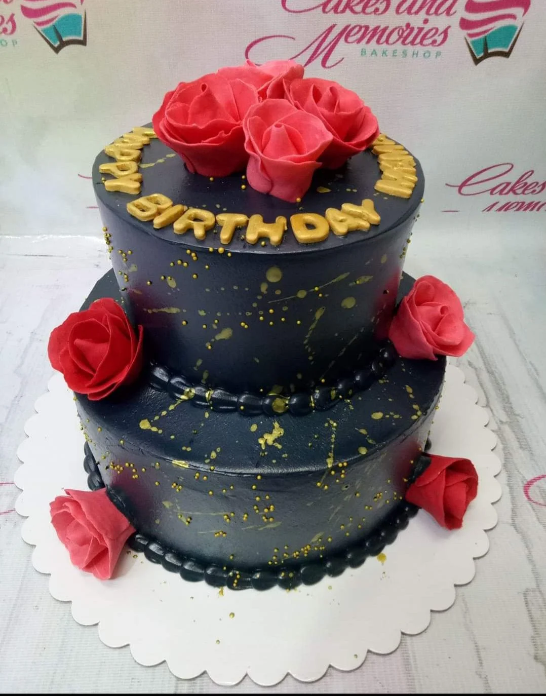 Navy Blue Floral 2-Tier Debut Cake Two-tier navy blue cake with red gumpaste roses and gold splatter accents for a birthday celebration.
