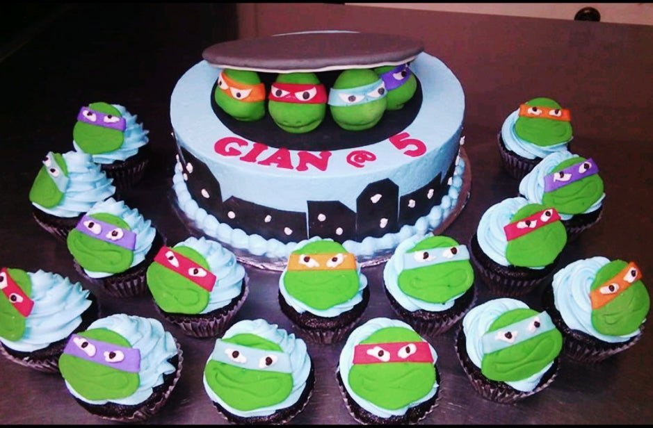 Teenage Mutant Ninja Turtles themed birthday cake with blue icing, city skyline, and matching cupcakes. Teenage Mutant Ninja Turtles themed birthday cake with blue icing, city skyline, and matching cupcakes.