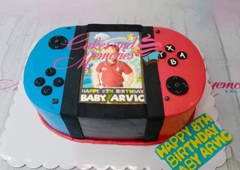 Nintendo Switch themed rectangle cake with blue and red icing, featuring a photo printout of a boy and black fondant buttons. Nintendo Switch themed rectangle cake with blue and red icing, featuring a photo printout of a boy and black fondant buttons.
