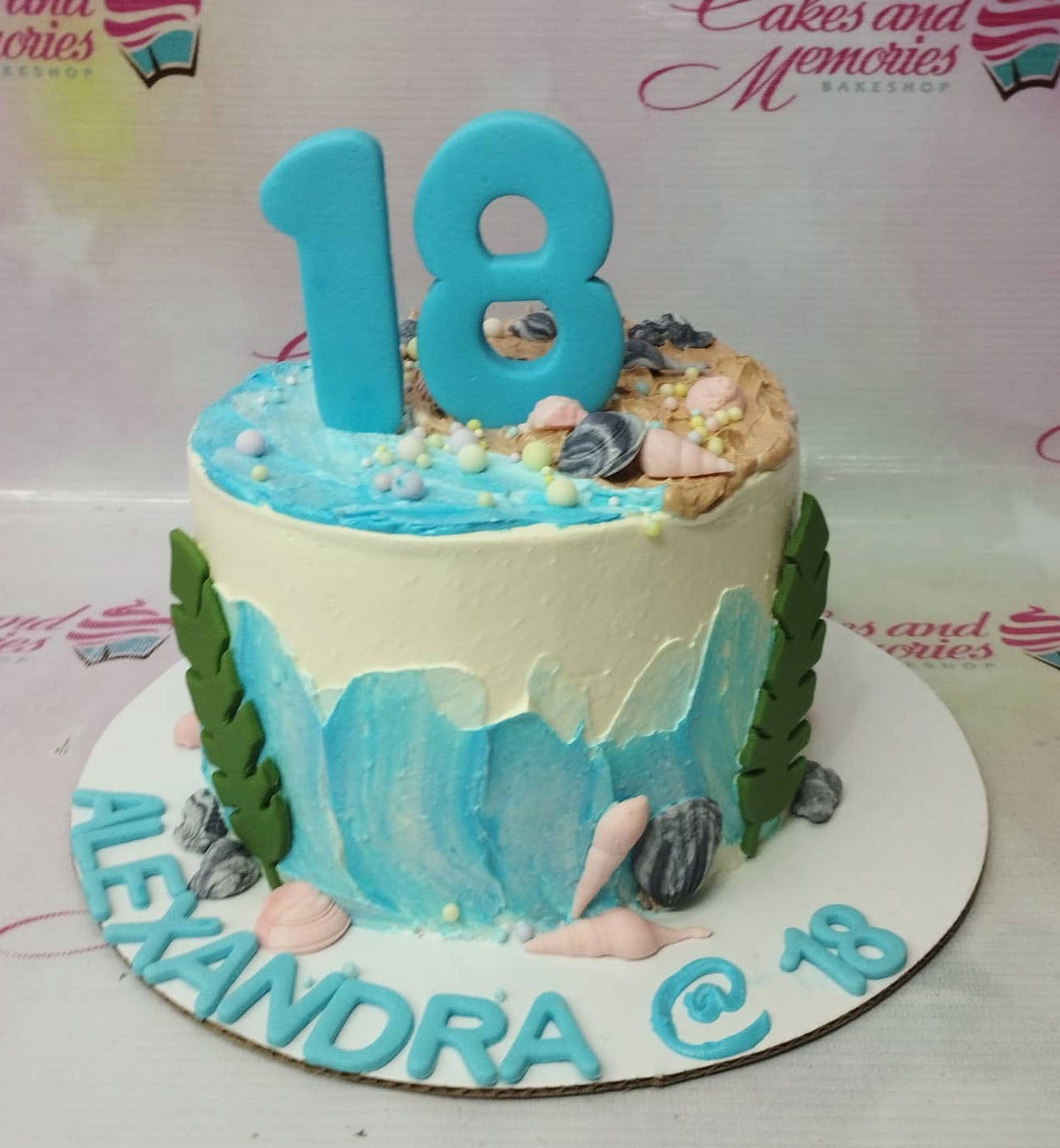 Ocean themed birthday cake with blue and white icing waves, edible seashells, and a large blue number 18 topper. Ocean themed birthday cake with blue and white icing waves, edible seashells, and a large blue number 18 topper.