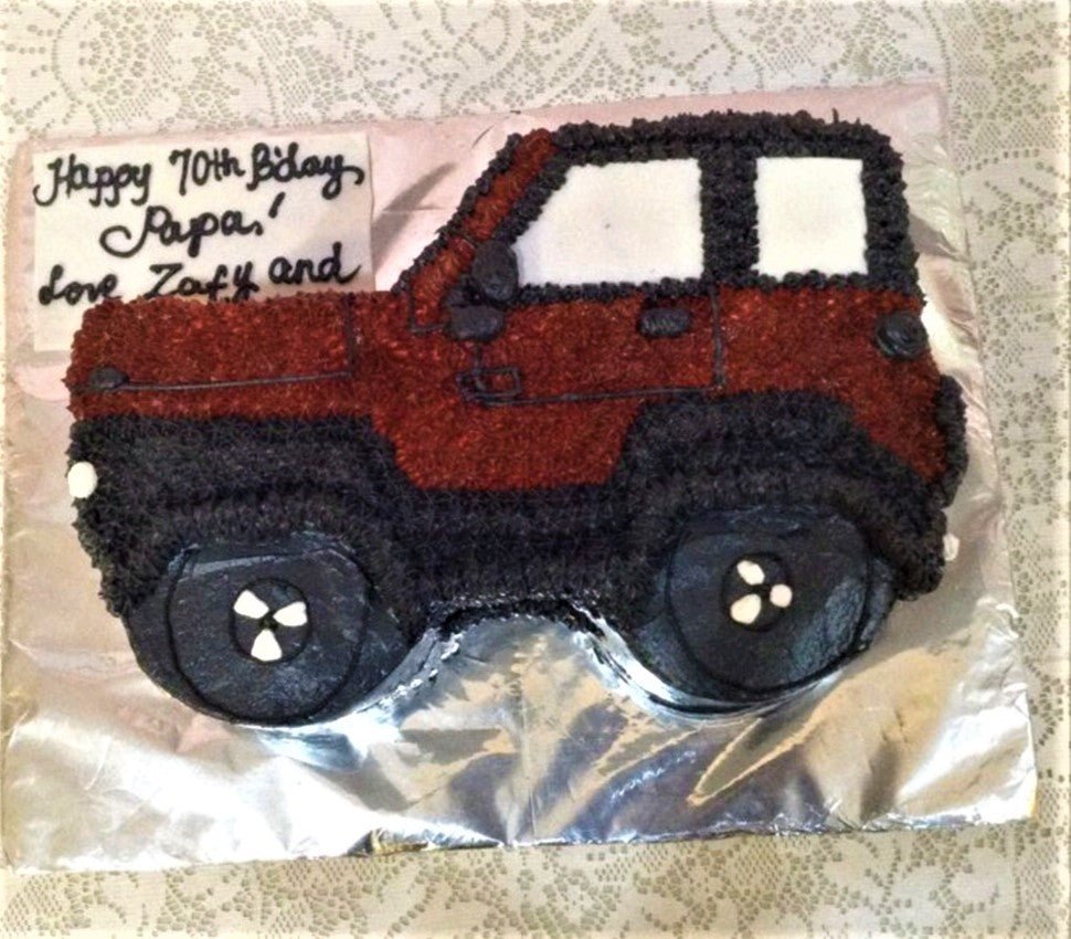 Red and black off-road vehicle shaped cake with piped icing details and a birthday message for Papa. Red and black off-road vehicle shaped cake with piped icing details and a birthday message for Papa.