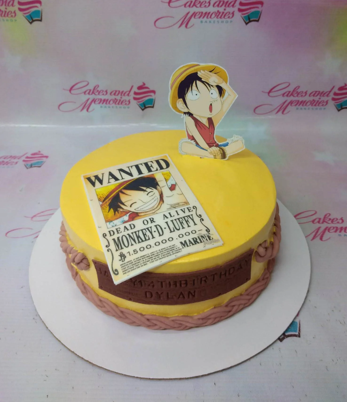 One Piece-Inspired Yellow Birthday Cake A yellow One Piece themed 1-tier cake, featuring Monkey D. Luffy printout toppers and a brown fondant message banner.