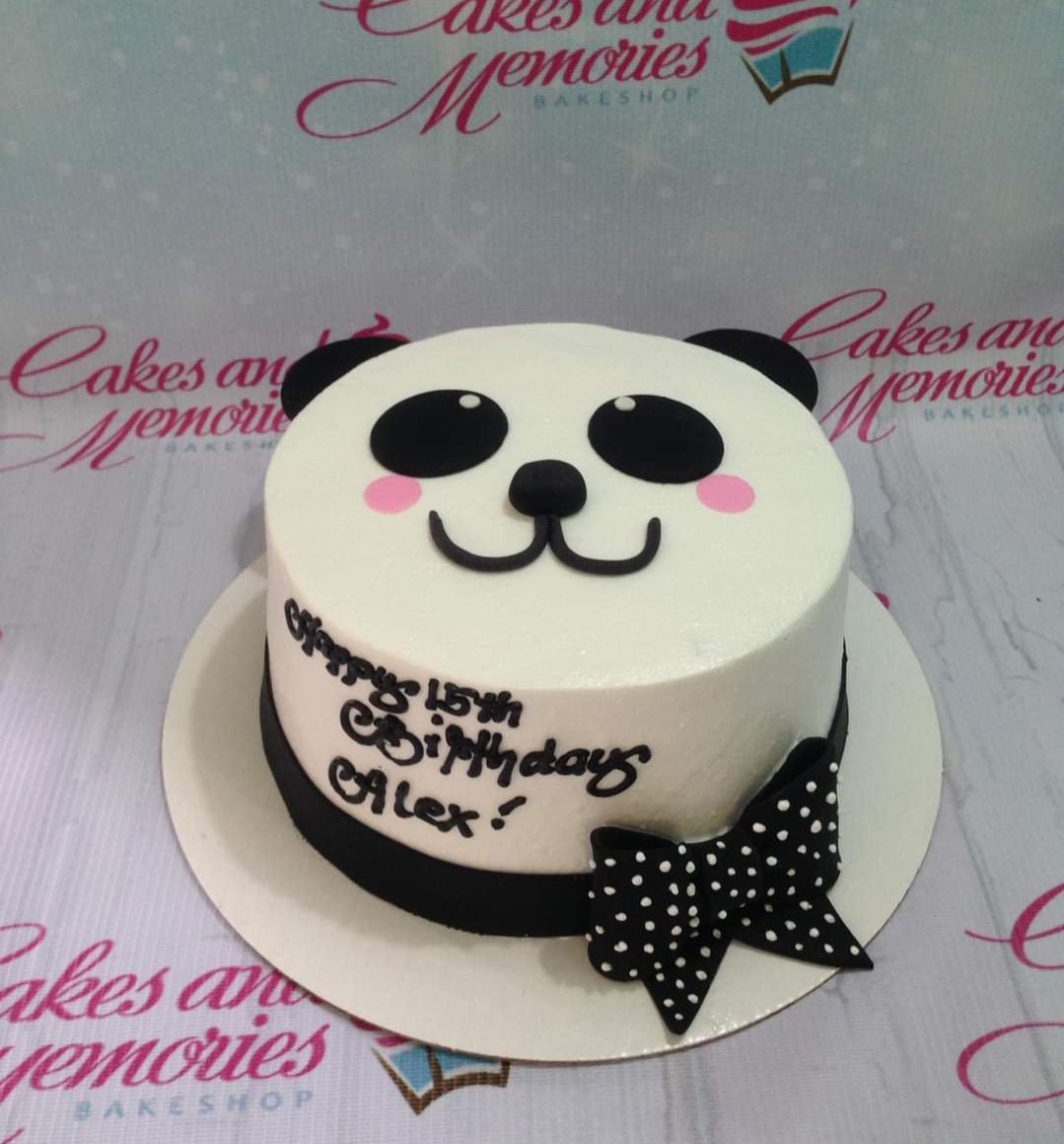 White panda-themed birthday cake with black fondant ears, eyes, and a polka dot bow. White panda-themed birthday cake with black fondant ears, eyes, and a polka dot bow.
