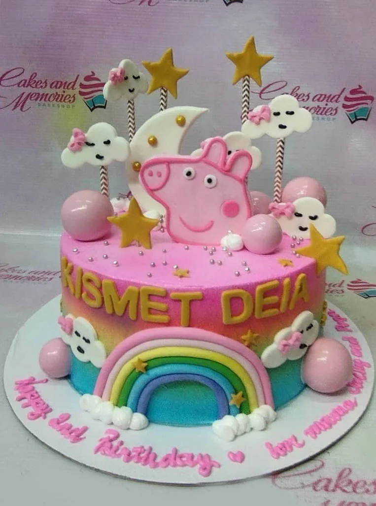 Pink Peppa Pig birthday cake with a rainbow, clouds, stars, and pink spheres on a colorful gradient icing base.