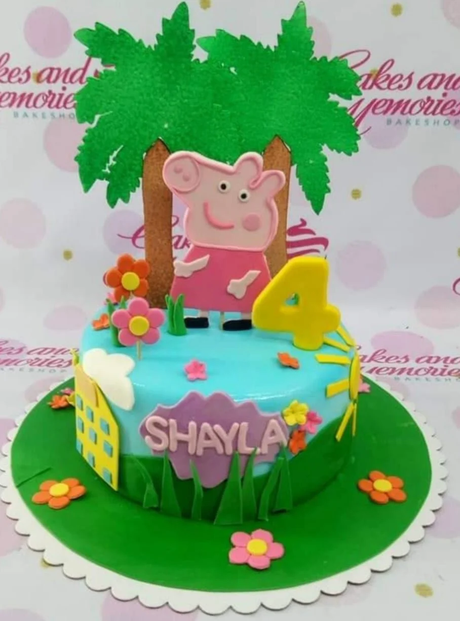 Peppa Pig themed birthday cake with a large Peppa figure, palm trees, and a yellow number 4 on a green base board.