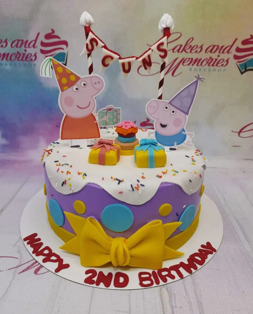 Peppa Pig themed purple and white birthday cake with fondant bow, polka dots, and character printouts.