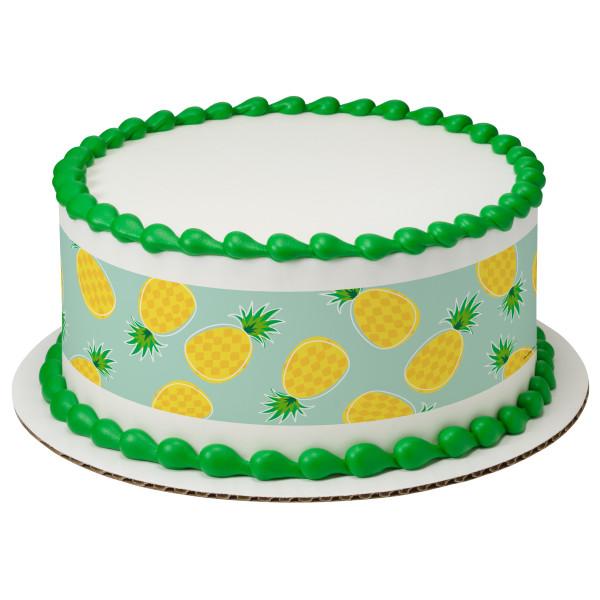 White round cake with green piped icing borders and a teal side wrap featuring yellow pineapple patterns. White round cake with green piped icing borders and a teal side wrap featuring yellow pineapple patterns.