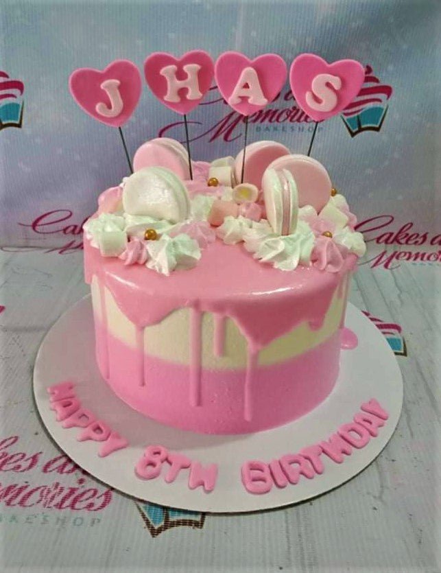 Pink and white two-tone cake with pink drip, macarons, marshmallows, and heart-shaped letter toppers for an 8th birthday. Pink and white two-tone cake with pink drip, macarons, marshmallows, and heart-shaped letter toppers for an 8th birthday.