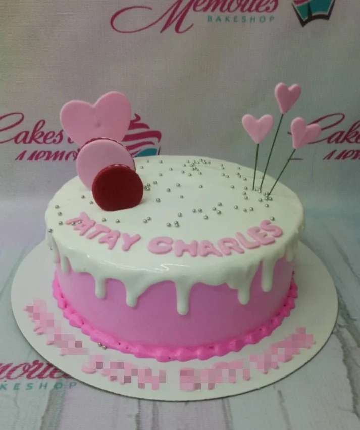 Pink and white drip cake with pink heart toppers, macarons, and silver dragees for a birthday celebration. Pink and white drip cake with pink heart toppers, macarons, and silver dragees for a birthday celebration.