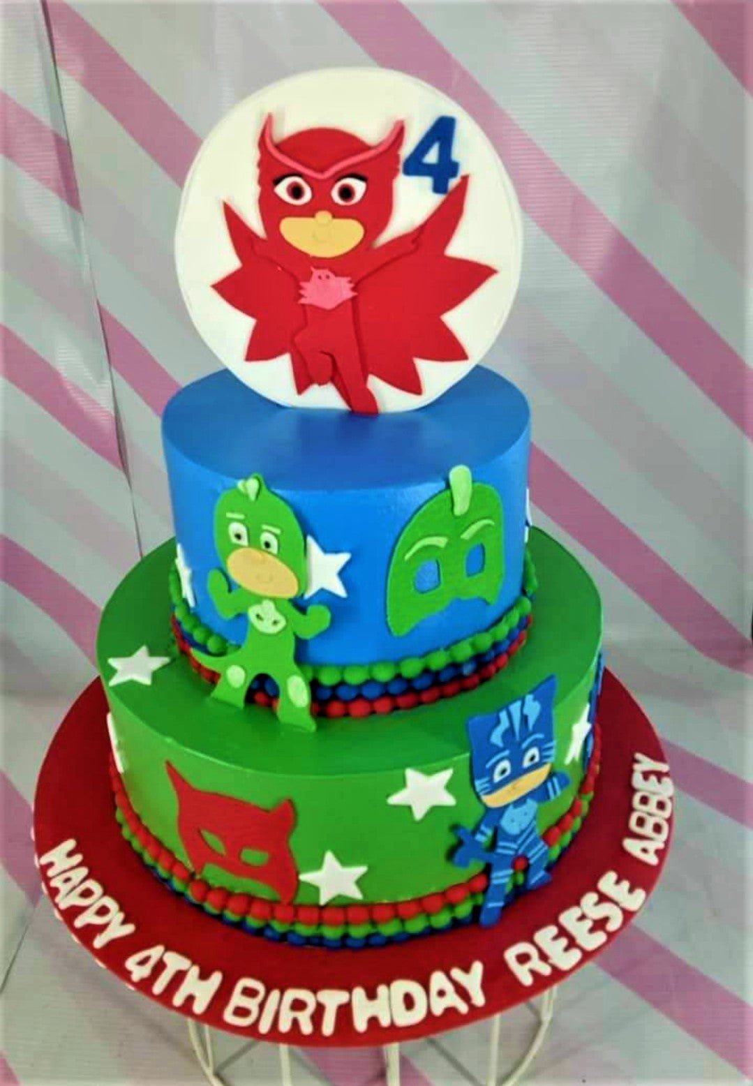 Two-tier PJ Masks themed birthday cake in blue and green fondant with Owlette, Gekko, and Catboy character toppers and stars. Two-tier PJ Masks themed birthday cake in blue and green fondant with Owlette, Gekko, and Catboy character toppers and stars.