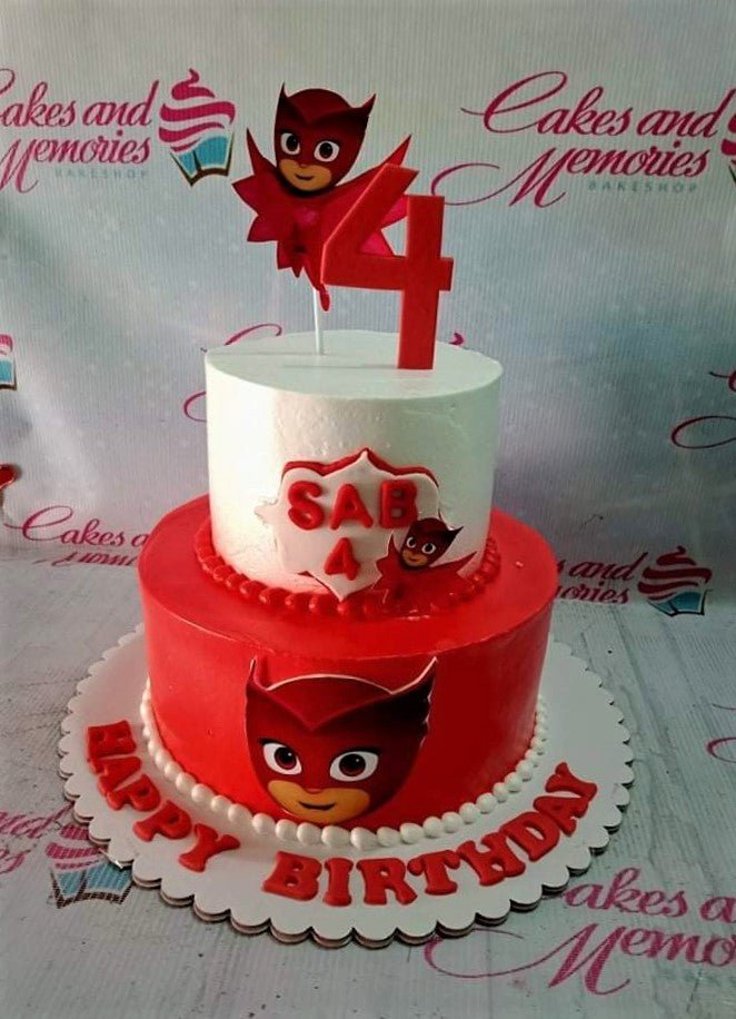 Two-tier red and white PJ Masks Owlette themed birthday cake with character printouts and a red number four topper. Two-tier red and white PJ Masks Owlette themed birthday cake with character printouts and a red number four topper.