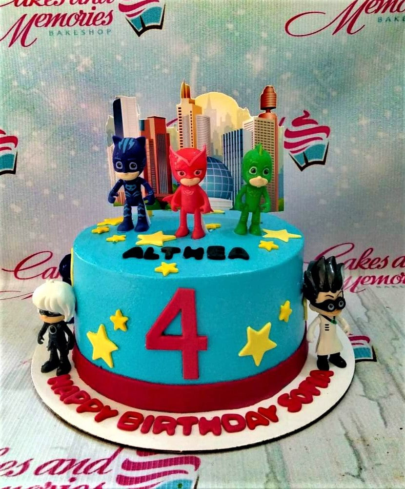 Blue PJ Masks themed birthday cake with 3D character figures, yellow stars, and a red number 4 on a light blue icing base. Blue PJ Masks themed birthday cake with 3D character figures, yellow stars, and a red number 4 on a light blue icing base.