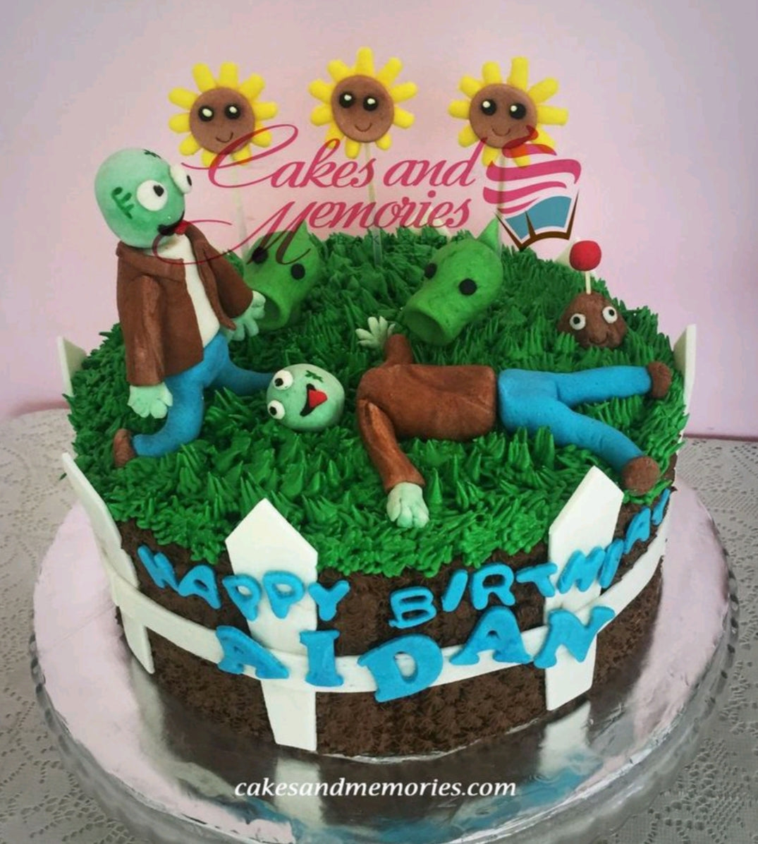 Plants vs Zombies themed birthday cake with fondant zombies, peashooters, and sunflowers on a green grass icing base. Plants vs Zombies themed birthday cake with fondant zombies, peashooters, and sunflowers on a green grass icing base.