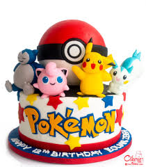 A white fondant cake featuring a Pokeball, Pikachu, Snorlax, Jigglypuff, and Pachirisu figures and colorful fondant stars. A white fondant cake featuring a Pokeball, Pikachu, Snorlax, Jigglypuff, and Pachirisu figures and colorful fondant stars.