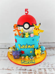 A light blue 1 tier cake featuring edible fondant Pokemon characters, a large Pokeball, and yellow and red star decorations. A light blue 1 tier cake featuring edible fondant Pokemon characters, a large Pokeball, and yellow and red star decorations.