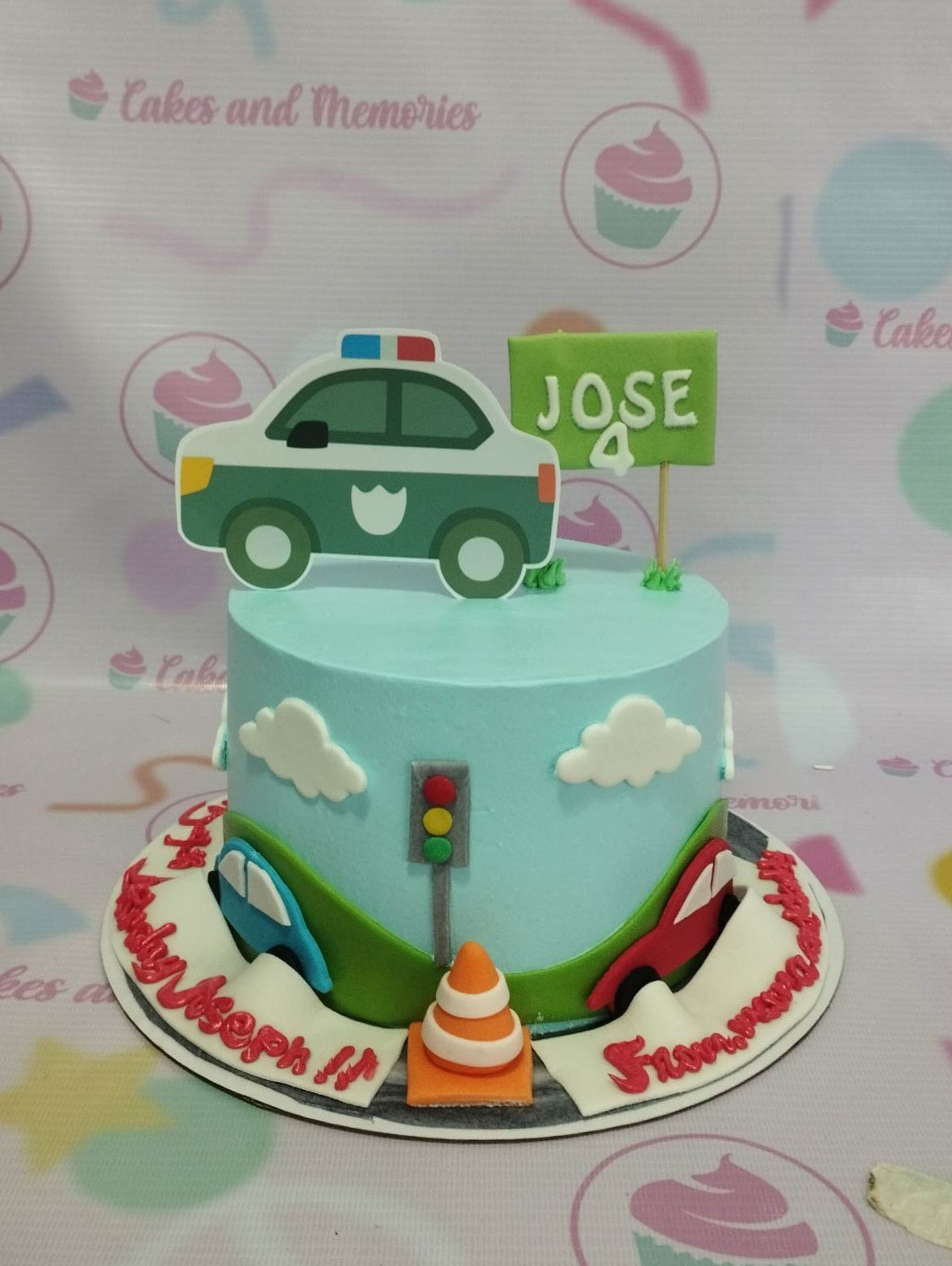 Light blue police car themed birthday cake with fondant clouds, traffic light, and a green name sign for Jose's 4th birthday. Light blue police car themed birthday cake with fondant clouds, traffic light, and a green name sign for Jose's 4th birthday.