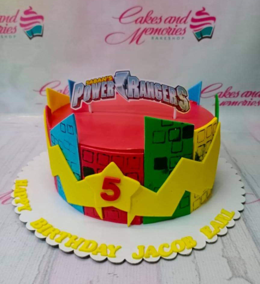 Power Rangers themed birthday cake with colorful city skyline panels and a yellow lightning bolt design. Power Rangers themed birthday cake with colorful city skyline panels and a yellow lightning bolt design.