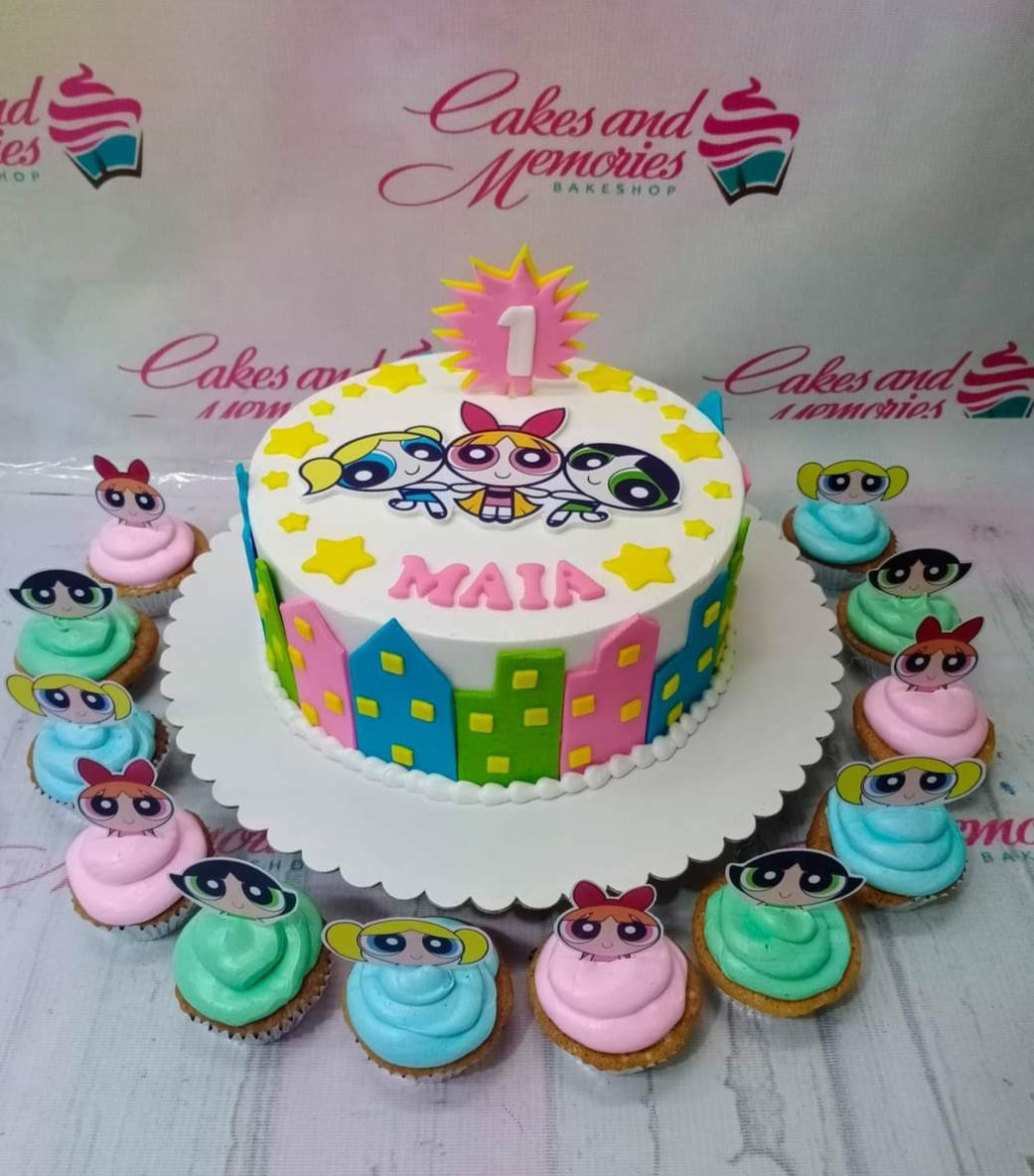 Powerpuff Girls themed birthday cake with colorful city skyline fondant panels and character printouts surrounded by matching cupcakes. Powerpuff Girls themed birthday cake with colorful city skyline fondant panels and character printouts surrounded by matching cupcakes.