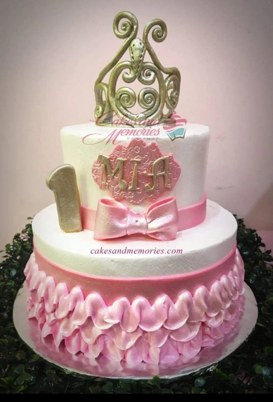 Princess Bow 2-Tier Birthday Cake Two-tier pink and white birthday cake with a large gold crown topper, pink bow, and ruffled icing on the bottom tier.