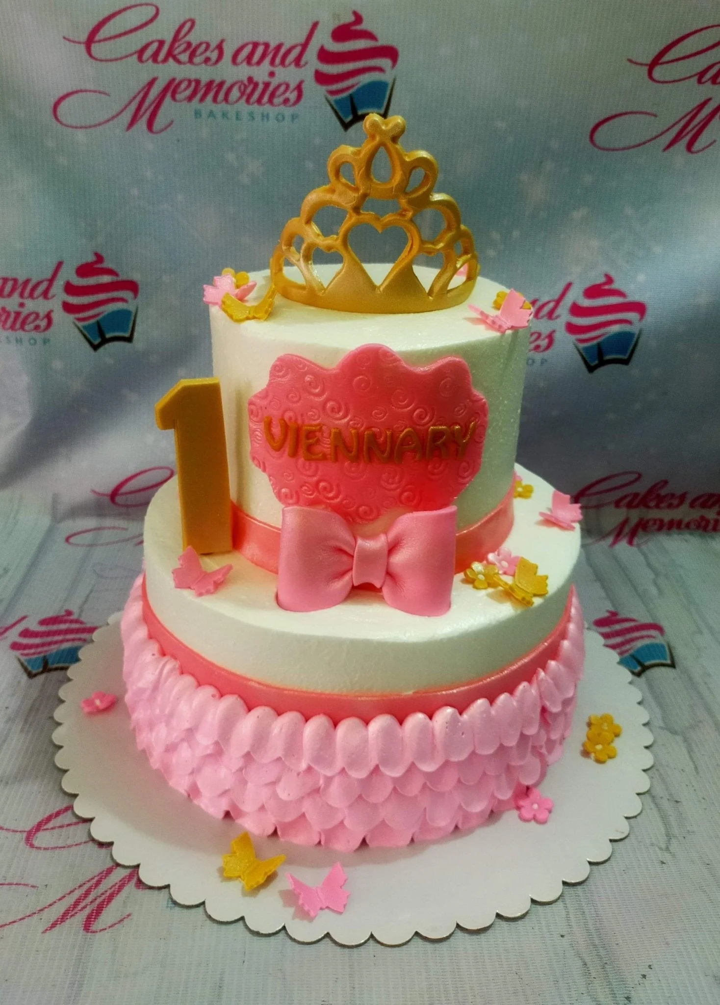 Princess Bow 2-Tier Cake Two-tier pink and white princess cake with a gold crown topper, pink bow, and butterfly decorations.