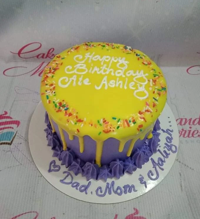 Purple Drip Birthday Cake A purple and yellow 1 Tier cake themed around Purple Drip, featuring yellow drip icing, colorful sprinkles, purple rosettes, and white text.
