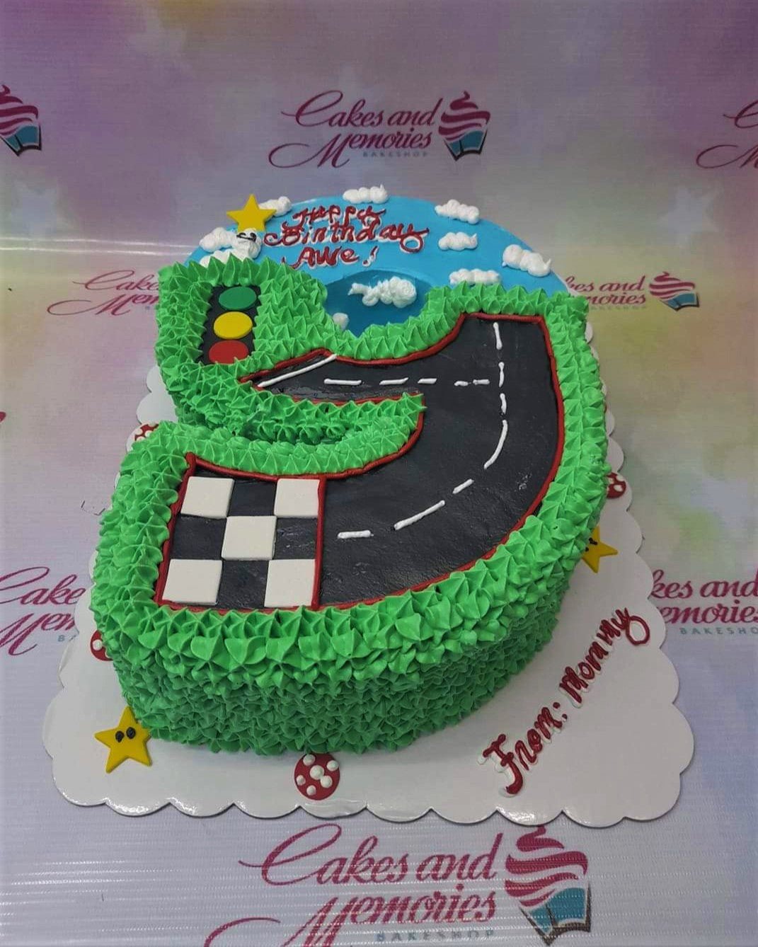 Number 3 shaped race track cake with green grass icing, checkered flag, and traffic light decorations. Number 3 shaped race track cake with green grass icing, checkered flag, and traffic light decorations.