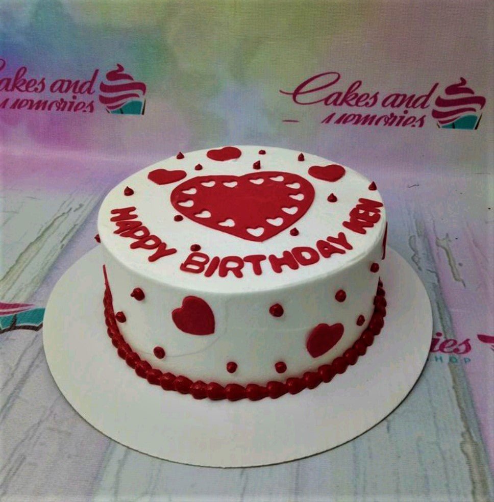 White minimalist birthday cake with red heart decorations and red piped icing text for Ken. White minimalist birthday cake with red heart decorations and red piped icing text for Ken.