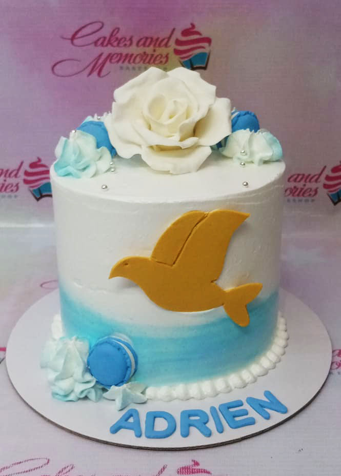 White and light blue ombre cake with a large white gumpaste rose, blue macarons, and a gold dove silhouette. White and light blue ombre cake with a large white gumpaste rose, blue macarons, and a gold dove silhouette.