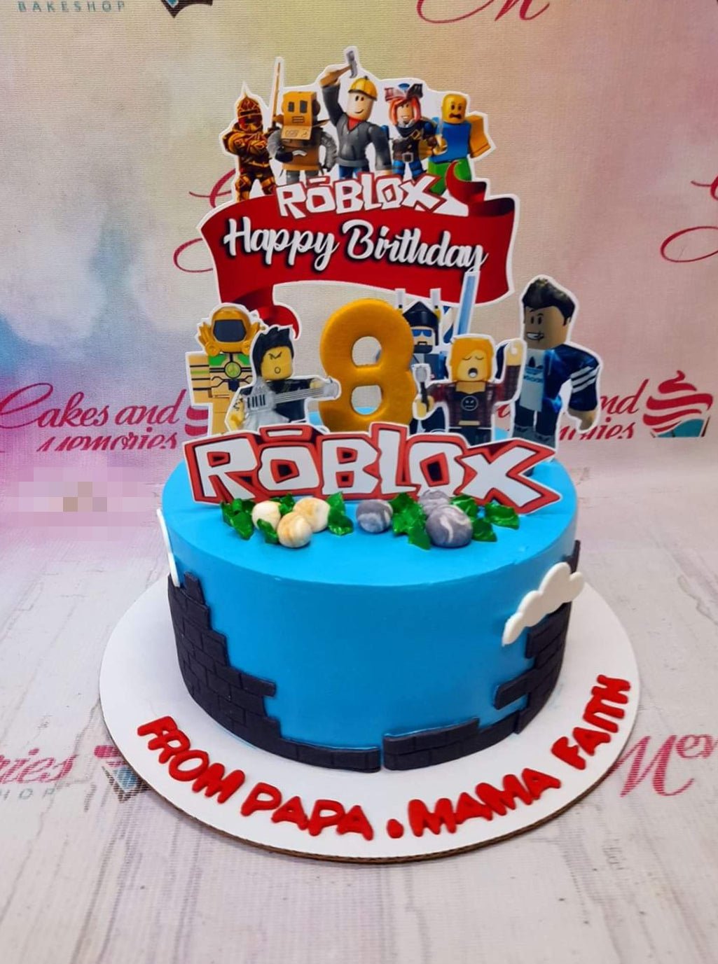 Blue Roblox themed birthday cake with character printouts, a gold number 8 topper, and brick wall icing details. Blue Roblox themed birthday cake with character printouts, a gold number 8 topper, and brick wall icing details.