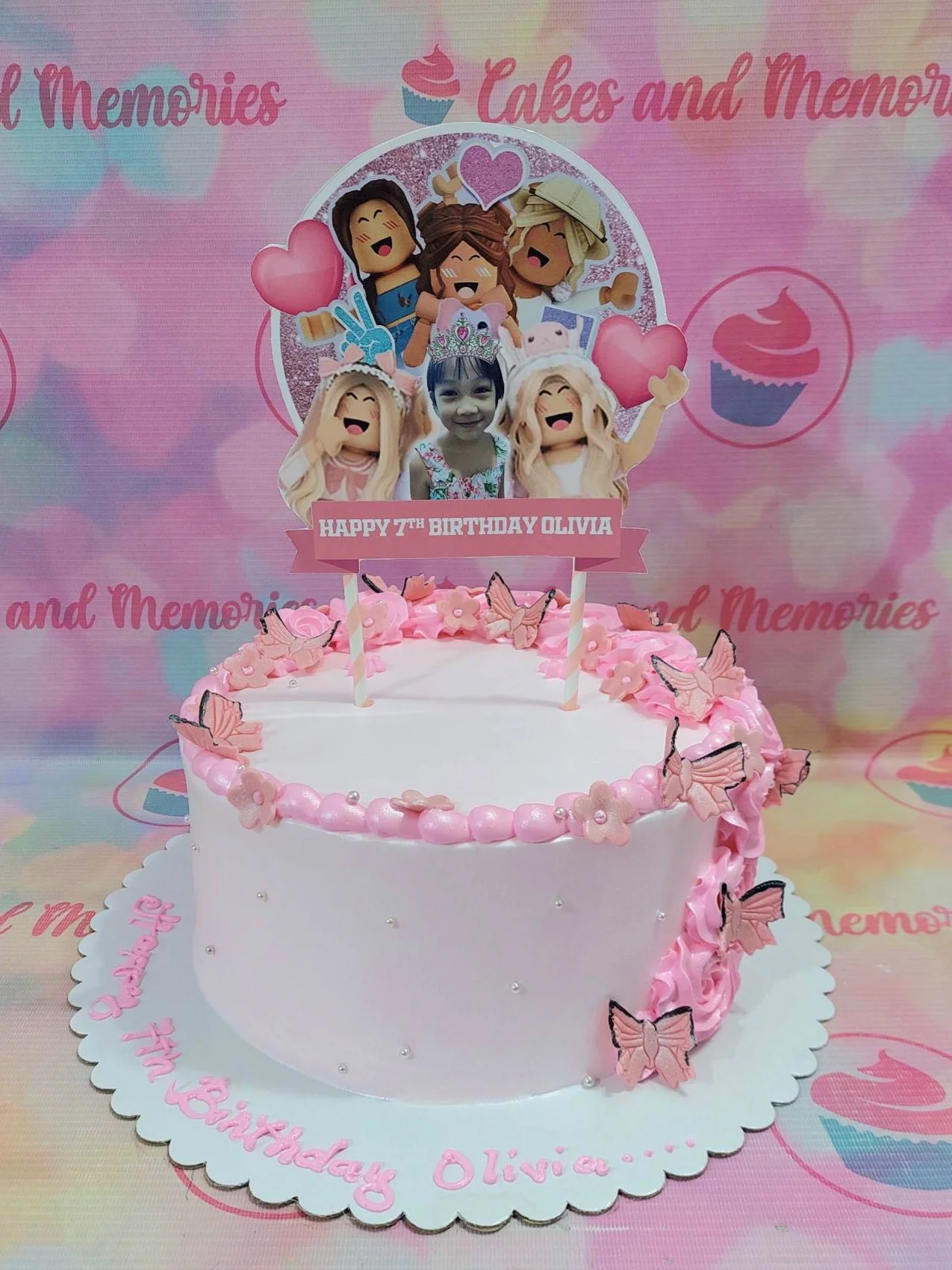 Pink Roblox themed birthday cake with a large character printout topper, pink icing rosettes, and butterfly decorations. Pink Roblox themed birthday cake with a large character printout topper, pink icing rosettes, and butterfly decorations.