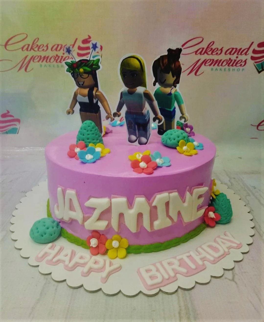 Roblox-Inspired Coral Floral Birthday Cake A pink and green 1-Tier cake themed around Roblox, featuring Roblox girl character printouts and flowers with bushes.