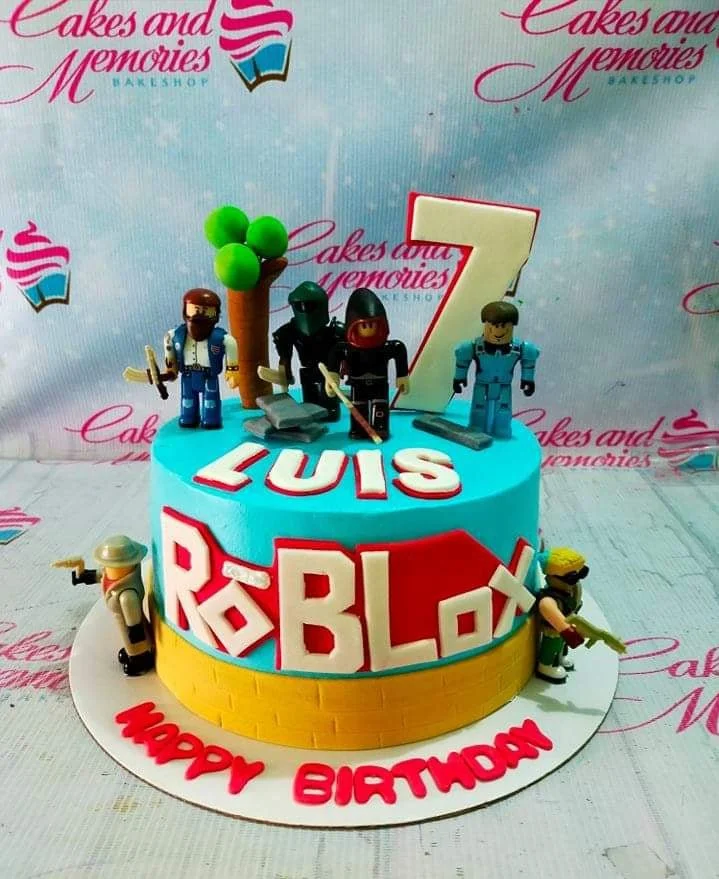 Roblox-Inspired Birthday Cake A blue and yellow 1 Tier cake themed around Roblox, featuring character figures, a large number 7, a brick pattern, and a Roblox logo.
