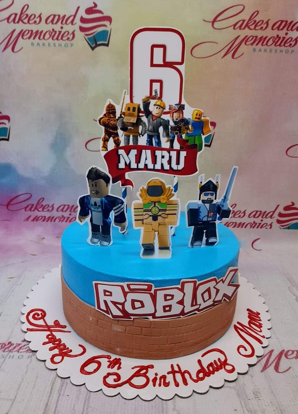 Roblox themed birthday cake with blue and brown brick icing, featuring various character printouts and a large number 6 topper. Roblox themed birthday cake with blue and brown brick icing, featuring various character printouts and a large number 6 topper.