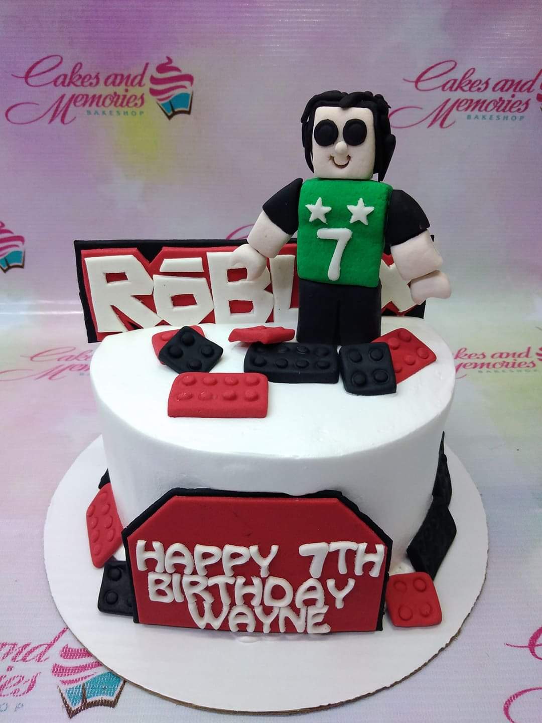 White fondant Roblox themed birthday cake with a 3D Roblox character topper and red and black building blocks. White fondant Roblox themed birthday cake with a 3D Roblox character topper and red and black building blocks.