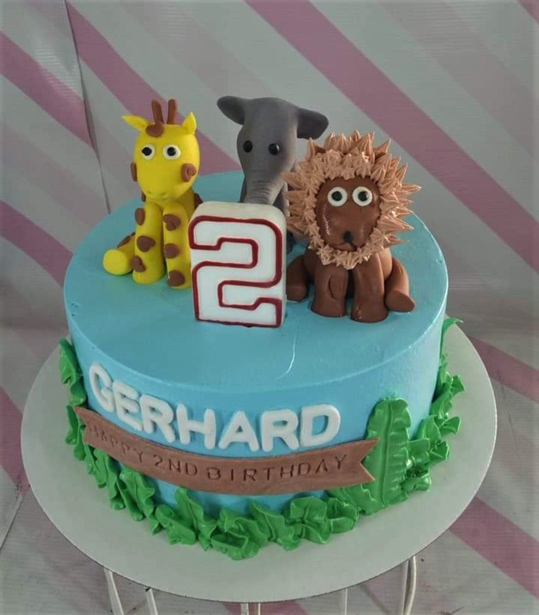 Light blue safari birthday cake with fondant giraffe, elephant, and lion toppers, green icing grass, and a number 2 candle. Light blue safari birthday cake with fondant giraffe, elephant, and lion toppers, green icing grass, and a number 2 candle.