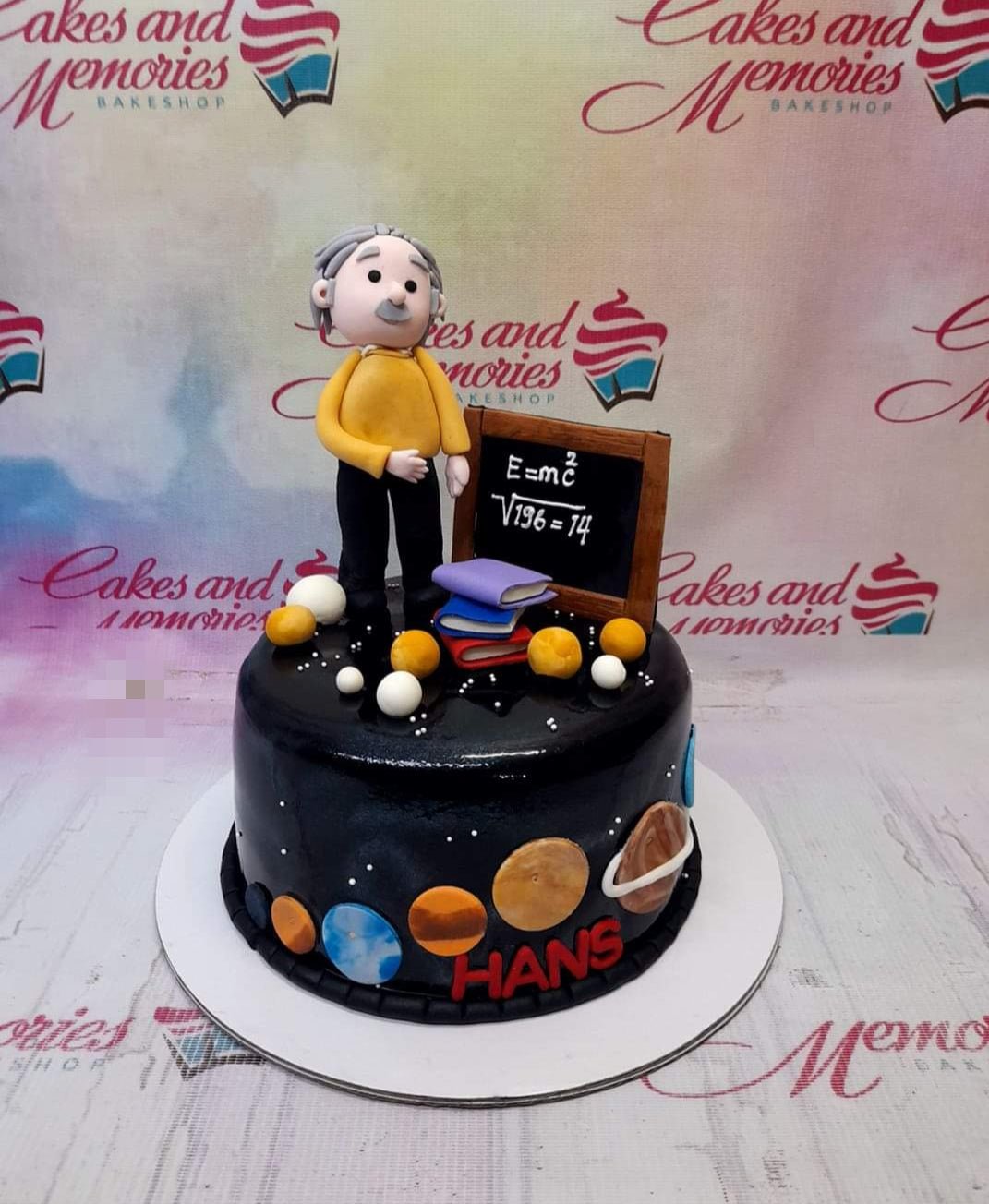 Black fondant science themed cake featuring an Albert Einstein figure, a chalkboard with E=mc2, and colorful planets on the side. Black fondant science themed cake featuring an Albert Einstein figure, a chalkboard with E=mc2, and colorful planets on the side.